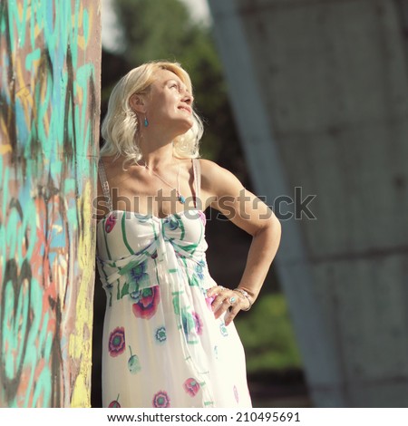 Portrait of beautiful senior blonde woman on the background of graffiti. Attractive senior lady portrait.