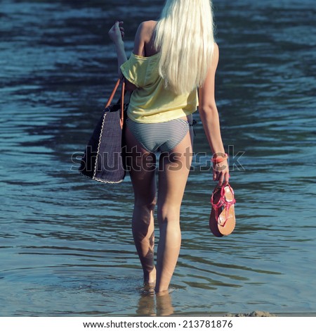 beautiful attractive girl came to the beach and went into the water. view from the back. Girl Walking On The Beach