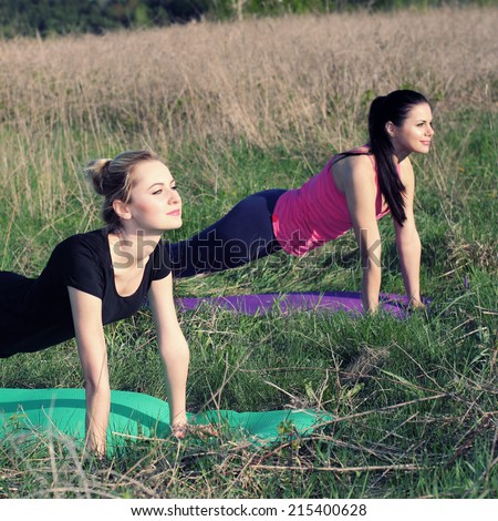 Two women doing yoga outdoors. yoga instructor shows poses