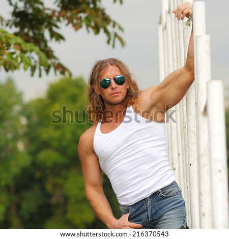 sexy caucasian fit man in sunglasses posing. Strong and confident man posing outdoor