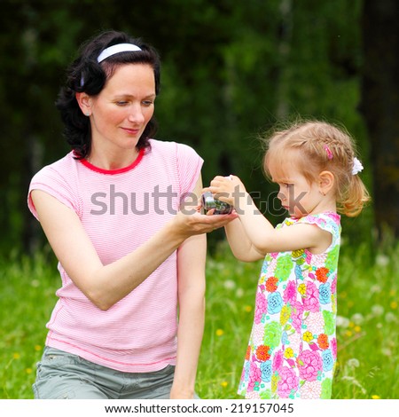little girl child to learn to photograph with his mother in the meadow. little baby pictures with mom
