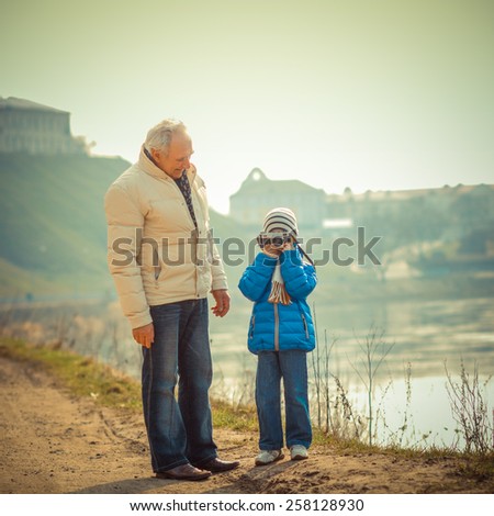 Grandfather and grandson are photographed on a vintage camera. Grandfather and grandchild in a landscape