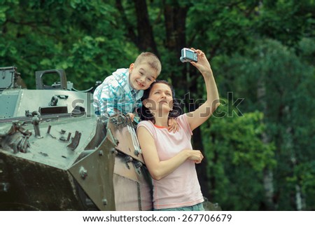 Mom takes pictures of his son on vintage military vehicle. Mom makes Selfe with his son against the backdrop of the historic military tank