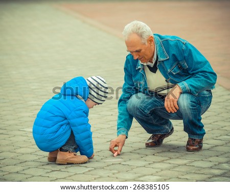 Grandfather and grandson draw with chalk on the road