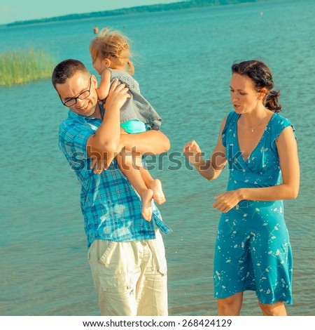 View of happy young family having fun on the beach. happy young family in a blue dress have fun at vacations on beautiful beach
