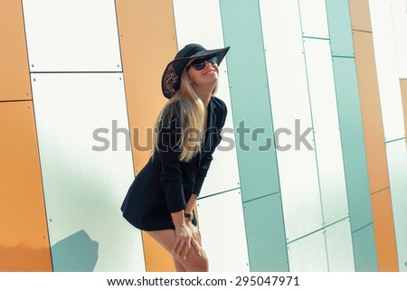 beautiful attractive trendy girl in long-skirted hat posing on the background orange wall