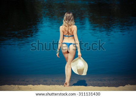 Beautiful female buttocks in bikini from the back. sexy woman buttocks on beach. summer holidays concept - back view of beautiful woman in bikini and a large wide-brimmed hat
