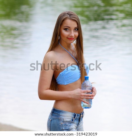 Girl on the beach drinking water. Portrait of young woman drinking water on beach