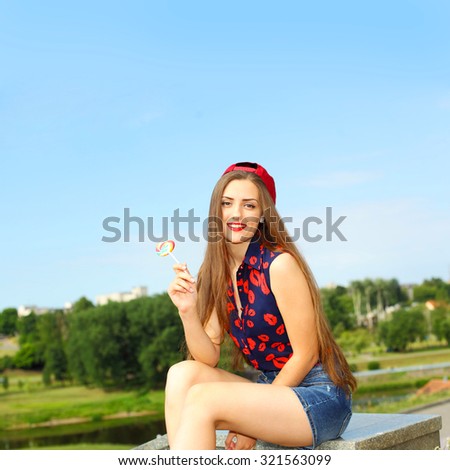 portrait of young sexy funny fashion girl with red lollipop. Young sexy girl sucking lollipop. Outdoors, lifestyle. positive and cheerful  hipster girl