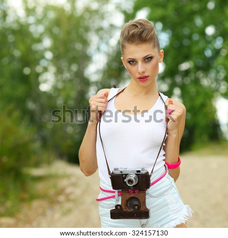 Hipster girl in shorts and a t-shirt with a vintage camera. modern hipster girl photographed using vintage camera. Outdoors lifestyle