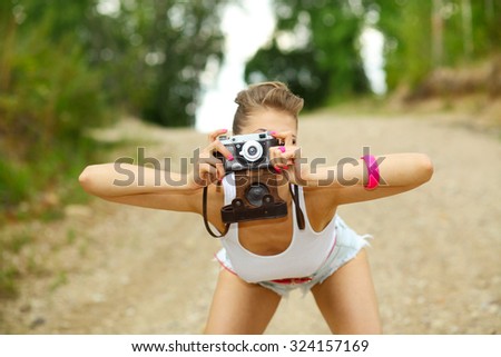 Hipster girl in shorts and a t-shirt with a vintage camera. modern hipster girl photographed using vintage camera. Outdoors lifestyle