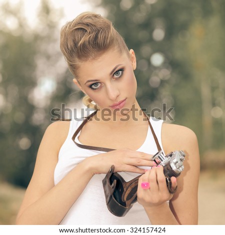Hipster girl in shorts and a t-shirt with a vintage camera. modern hipster girl photographed using vintage camera. Outdoors lifestyle. Vintage toning