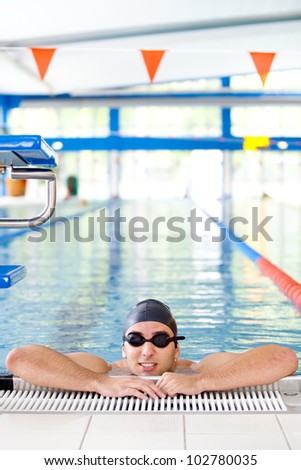Male Swimmer resting after several laps in the indoor swimming pool