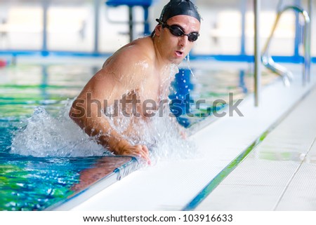 Portrait of young man finishing swimming training, getting out of pool