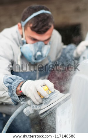 Young auto mechanic using the power buffer machine for painting the car
