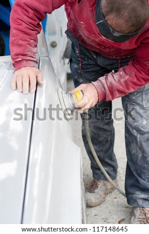Auto mechanic preparing the car for paint job by applying polish with the power buffer machine