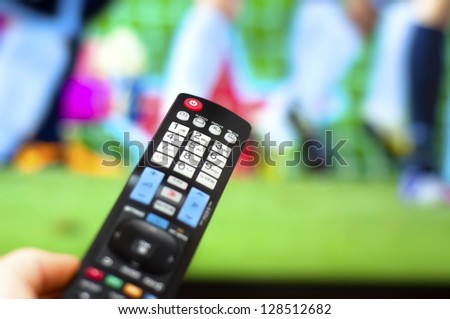 Close-up of modern remote control, watching a soccer game on TV