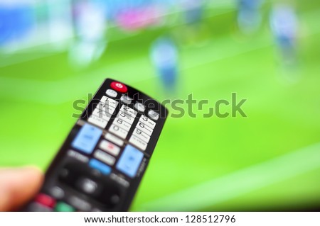 Watching soccer game on modern tv, with a close-up of the remote control