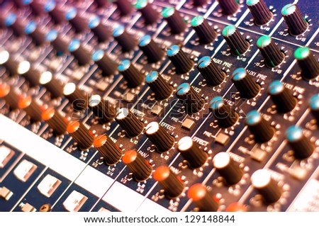 Music mixer with close-up of controls in nightclub with colorful lights