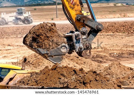 Close-up of heavy duty excavator scooping into earth and loading a dumper truck
