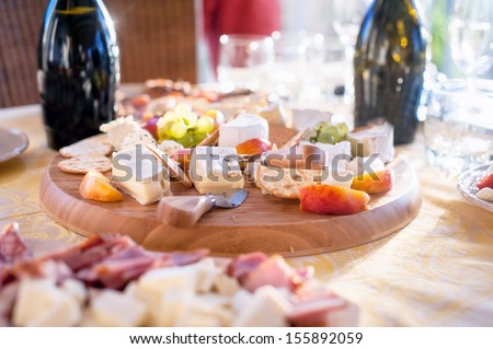 Cheese and fruits as appetizer with various types of cheese in background at dinner party