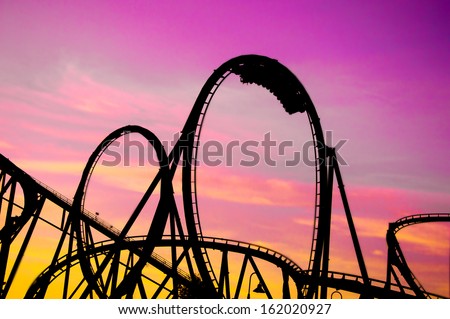 colorful silhouette of a roller coaster at sunset, after a sunny day at entertainment park