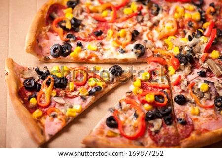 Italian Pizza closeup with a cut slice. Pizza with ham, pepperoni, olives,  corn and peppers