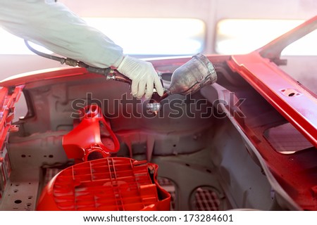 worker painting a car element, the hood with special paint and tools