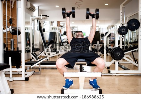 young man training at gym with dumbbell, chest bench exercise