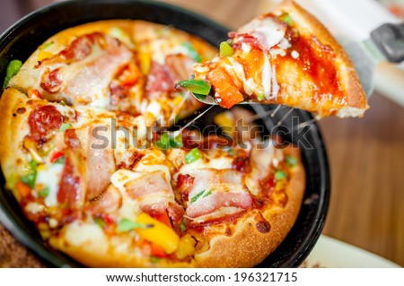 Hot cannibal slice of pizza with extra bacon, ham and vegetables served in hot iron plate