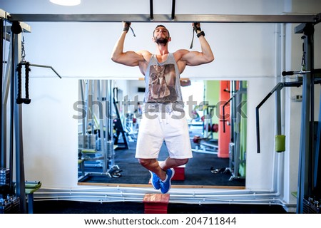 Sexy bodybuilder model working out the back exercises, doing chin ups at the gym