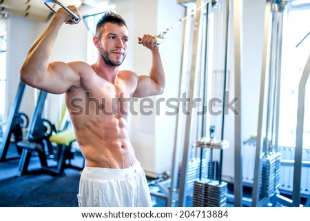 Topless man, bodybuilder and muscular man working the biceps at gym, showing abs
