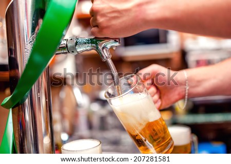 close-up of barman brewing a draft beer at pub. Bartender pouring beer in a mug