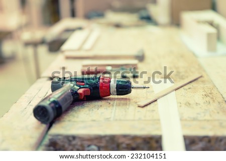 Cordless drilling screwdriver machine at industrial wood and steel factory on wooden board