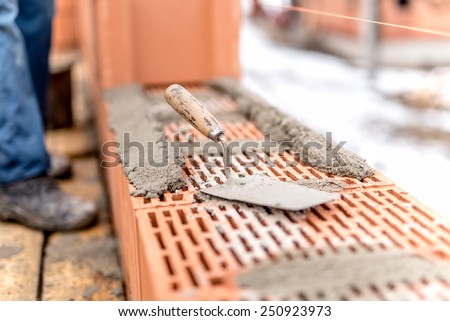 Detail of construction site, trowel or putty knife on top of brick layer