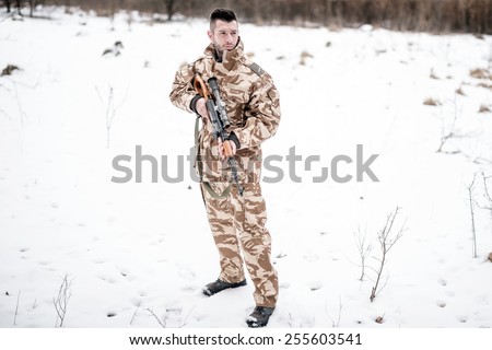 Army ranger with automatic machine gun performing patrol in a snowy forest