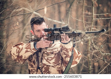 Man holding a sniper and shooting on an open season, looking through scope