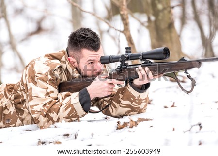 Hunter with a sniper rifle shooting during winter open season