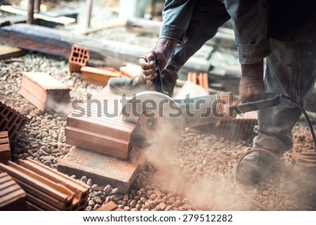 Industrial construction worker using a professional angle grinder for cutting bricks and building interior walls