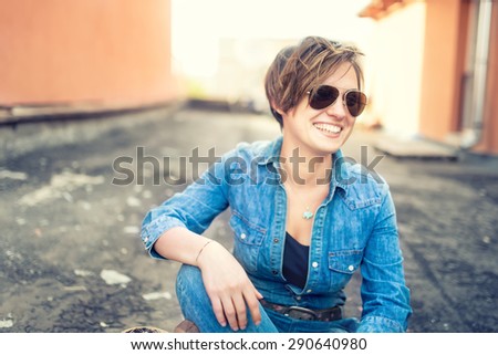 portrait of beautiful girl with sunglasses laughing and smiling while talking with friends, hanging out on roof of building. Young active lifestyle people concept
