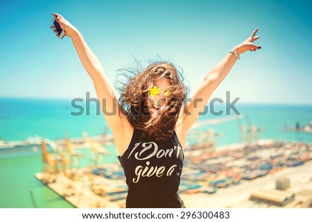 Attractive girl wearing black tank top smiling, laughing and taking pictures with camera phone. Traveling concept with happy woman. Soft colorful effect on photo
