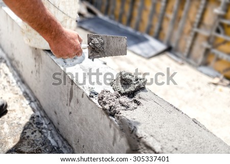 Construction worker leveling concrete with putty knife at building site. Details of construction industry
