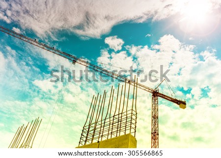 Industrial construction crane building skyscrapers and houses. Crane silhouette on construction site, industrial tools closeup. Soft, vintage effect on photo