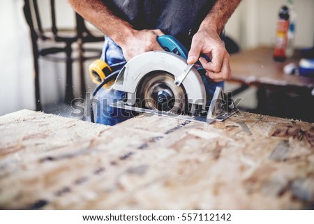 Carpenter using circular saw for cutting wooden boards. Construction details of male worker or handy man with power tools Сток-фото © 
