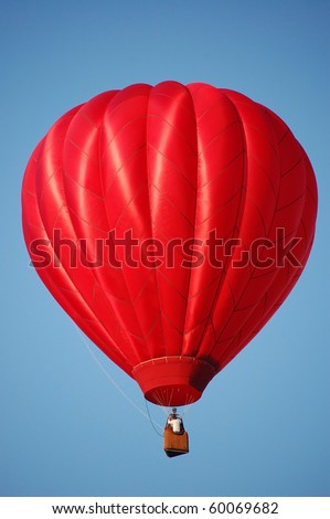 A red hot-air balloon in the sky on a beautiful summer morning.