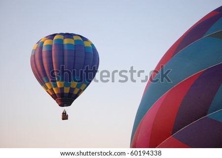 A blue hot air balloon rises into the sky on a bright summer morning.
