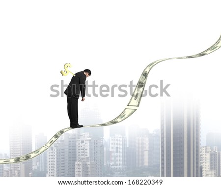 Businessman with money symbol winder on his back standing on growing money trend with city view background