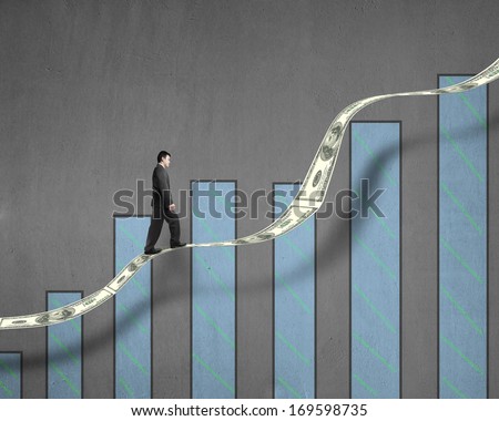 Businessman walking on growth money trend with chart in concrete wall background