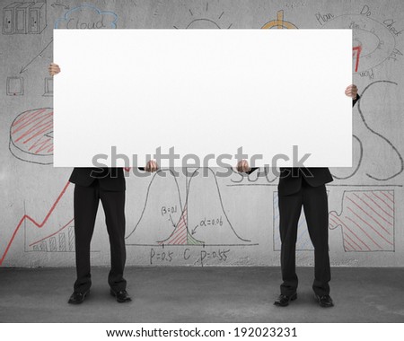 Two man holding board with business doodles on concrete wall
