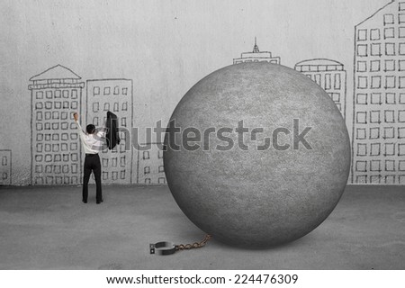 cheering businessman free from concrete ball shackle with doodles wall
